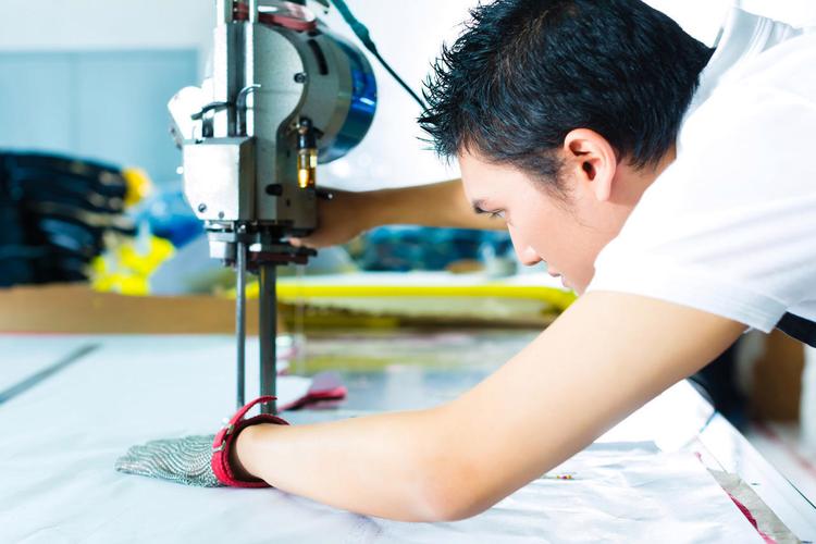 在中国的一家纺织厂里他戴着一副手套在工作那是一台用来切割布料的大